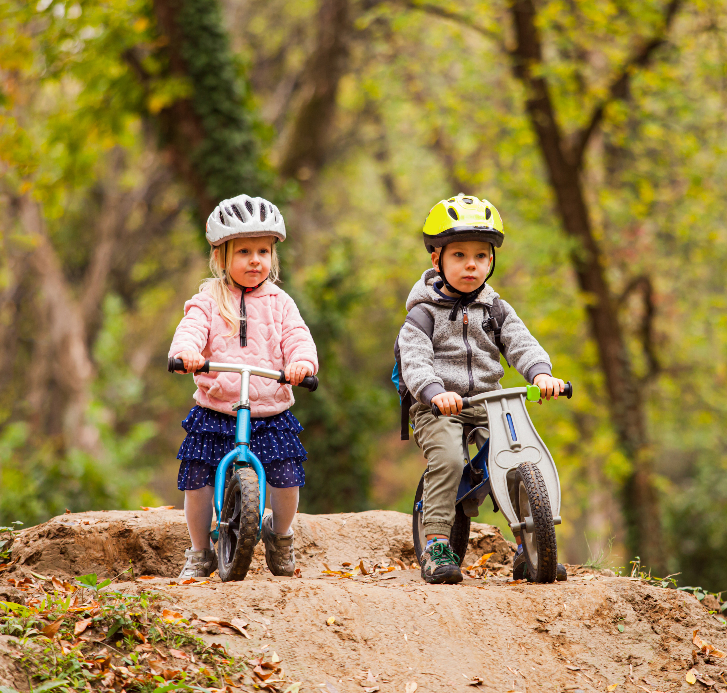 Børnehavebørn cykler ned af bakke på løbecykler.